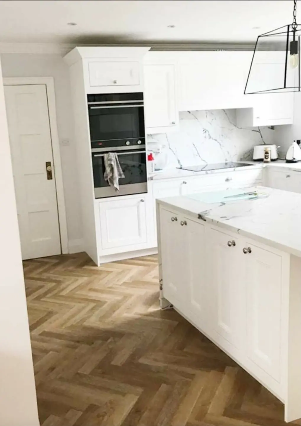 Shaker-style kitchen with a marble-effect island and herringbone flooring